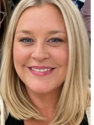 Close-up portrait of a smiling blonde woman with blue eyes.