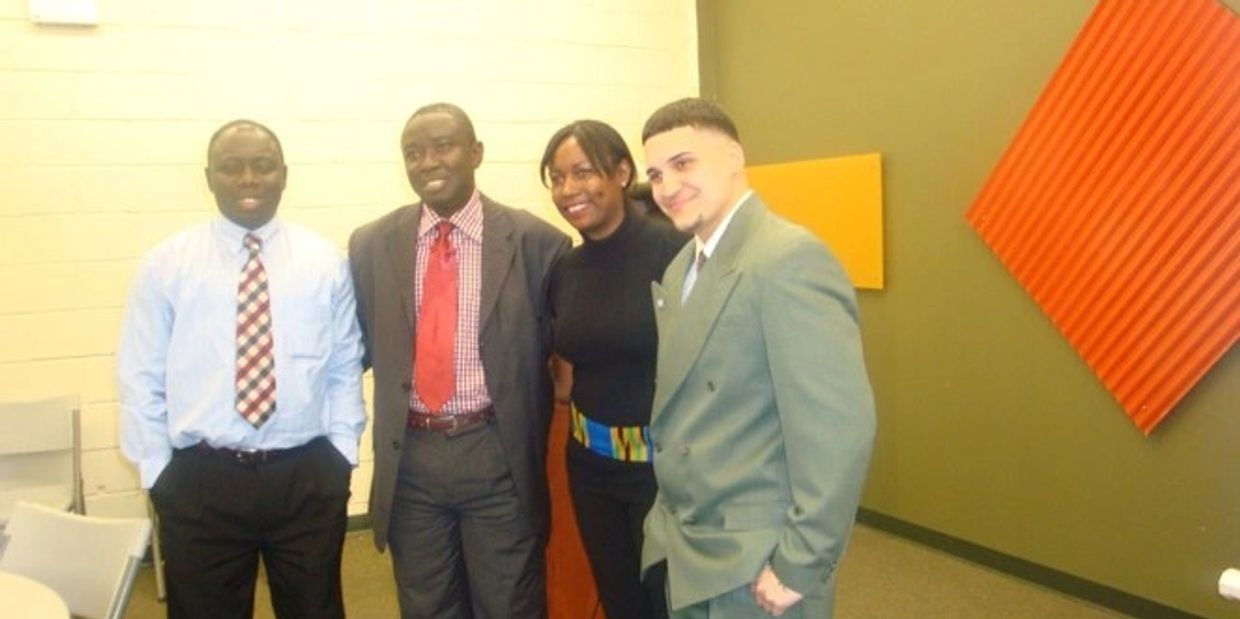 Four people dressed formally, posing indoors with smiles.