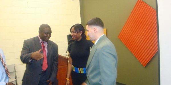 Three professionals in formal attire engaged in conversation at an indoor event.