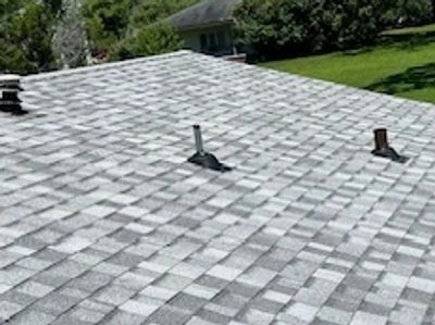 Gray shingled roof with two pipes extending upward.