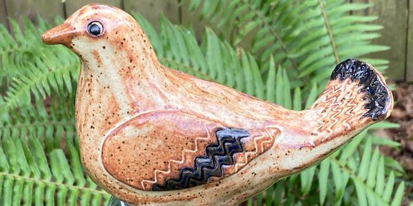 Decorative ceramic bird sculpture with intricate patterns and earthy tones.