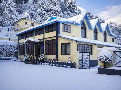 Snow-covered house with a bright yellow exterior in a winter landscape.
