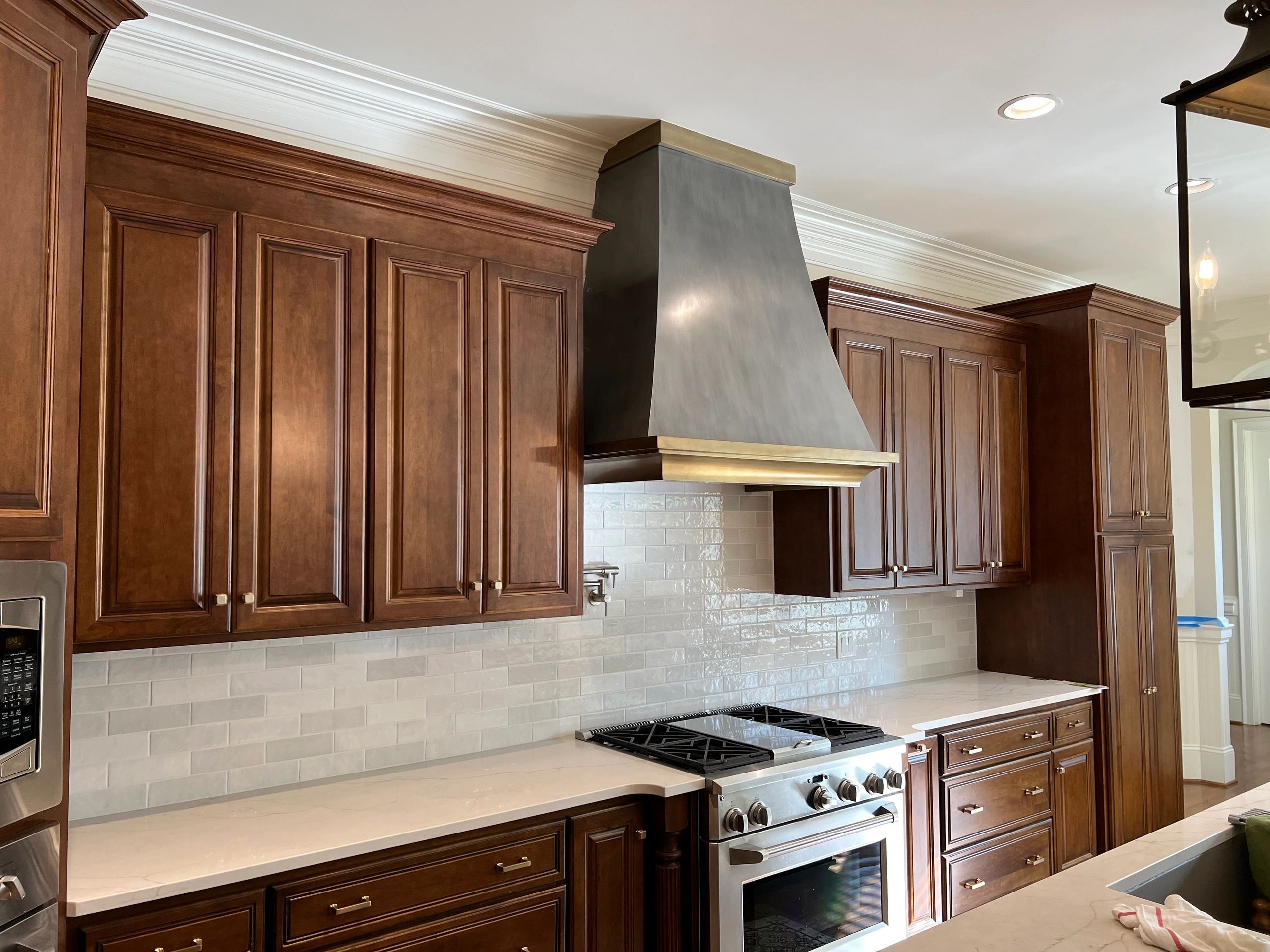 Finished kitchen renovation with custom dark wood cabinetry, stone countertops, tile backsplash, pro
