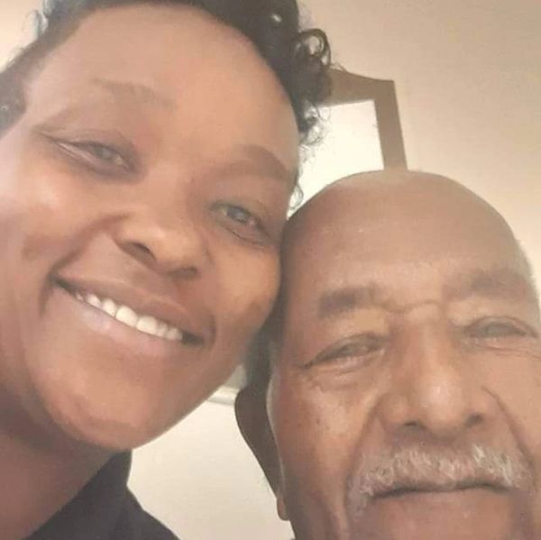 Smiling elderly man and woman posing closely for a selfie indoors.
