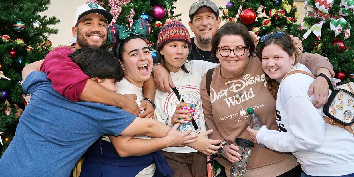 Group of happy people embracing in front of Christmas trees.