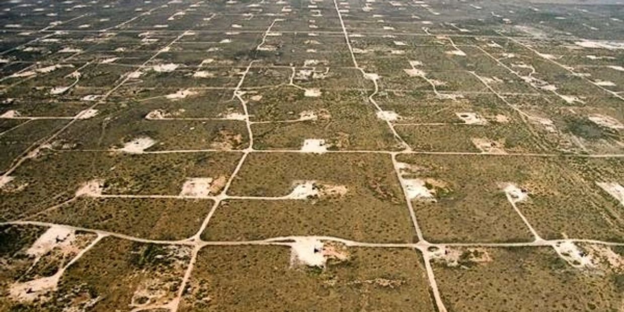 Aerial view of barren land plots with dirt roads forming a grid pattern.