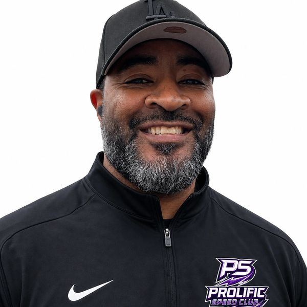 Man smiling wearing a black Prolific Speed Club jacket and cap.
