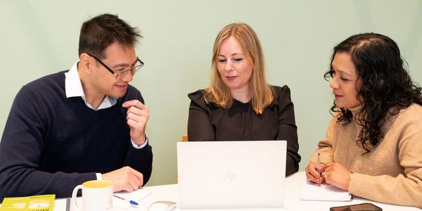 Image of Susie Horan working with two coaching clients at a desk. 