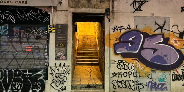 A dimly lit alley between two heavily graffitied buildings. 