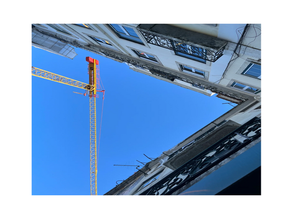 A photo taking facing to the sky with two wings of a building and a crane forming a triangle.