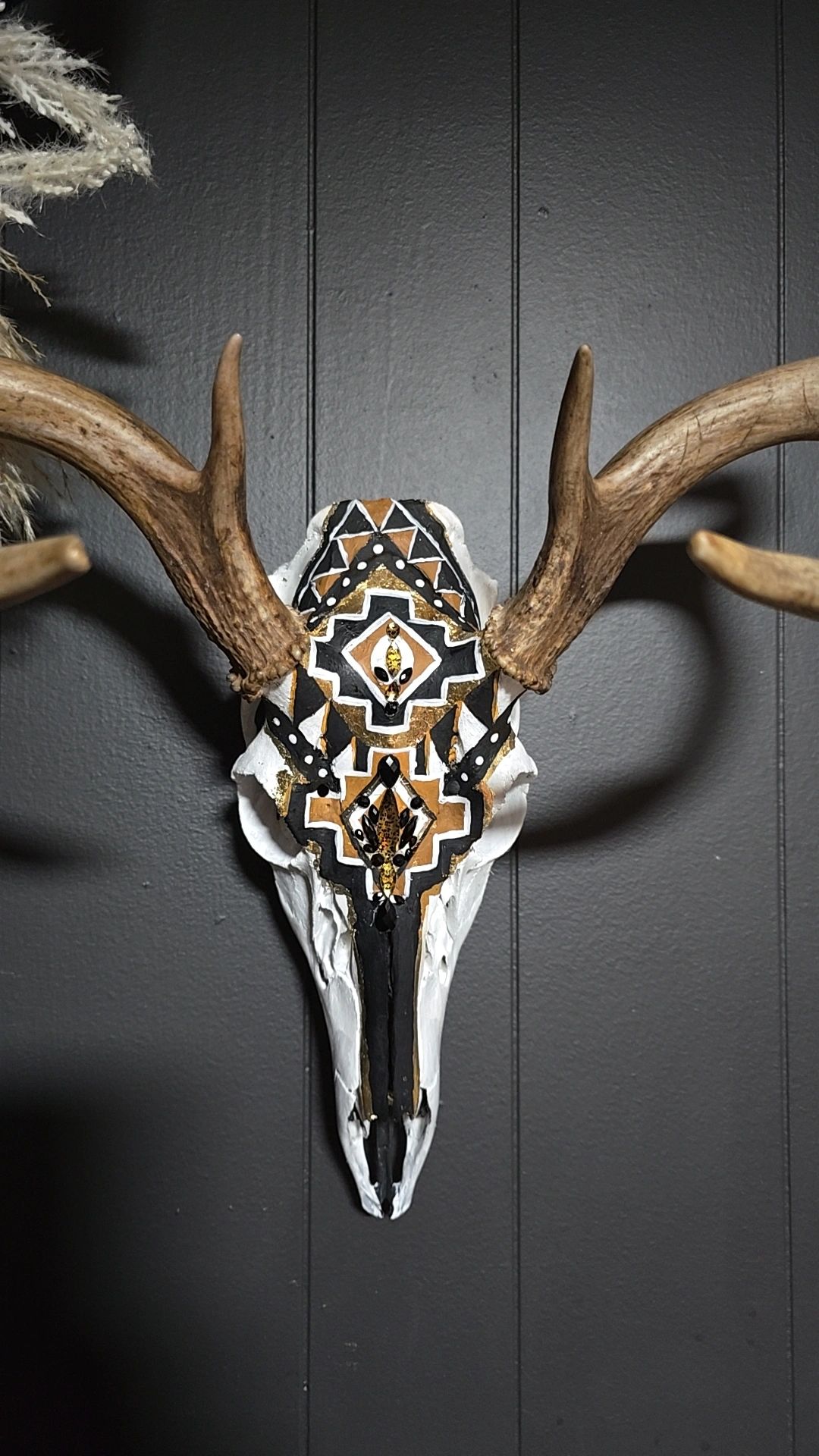 Decorative deer skull with intricate black, gold, and white geometric patterns.