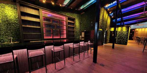 Bar and lounge with seating, illuminated shelves and greenery in an NRG Lux virtual tour.