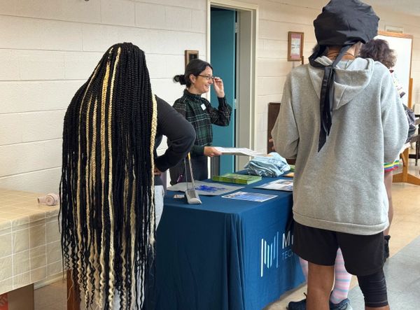 People interacting at a table with informational materials indoors.