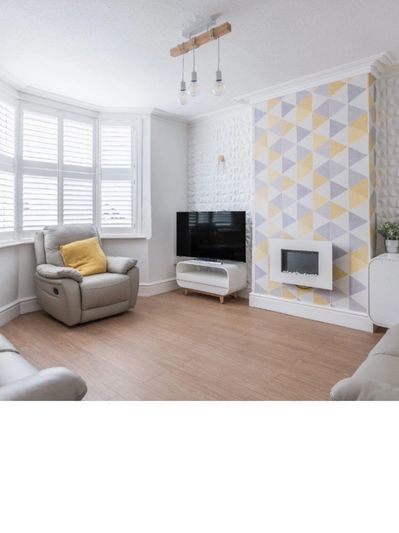 Modern living room with geometric wallpaper and a cozy armchair.