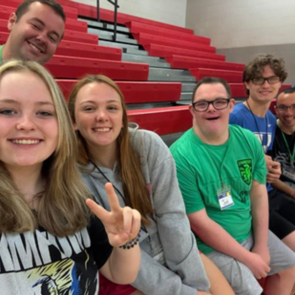 Group of friends smiling in gym bleachers.