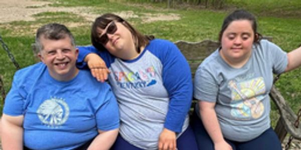 Three friends sitting on a park bench, smiling and relaxed.