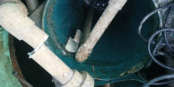 Inside view of a green water tank with pipes and cables.