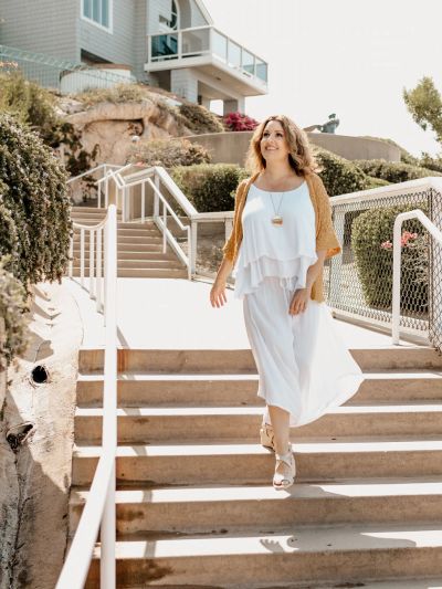 Woman in white dress walking down outdoor stairs.