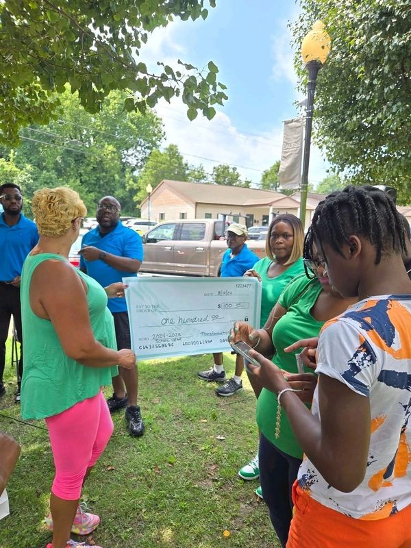 Group holding large check outdoors in casual clothes.