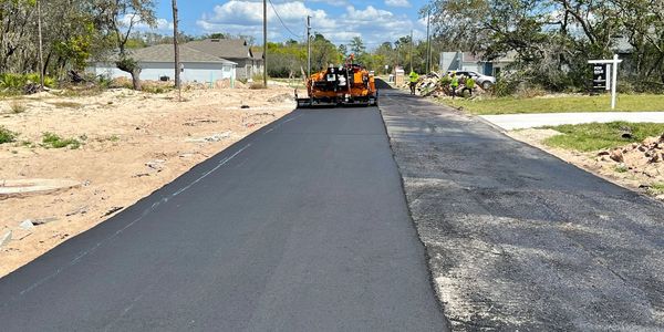 Road paving in progress with fresh asphalt.