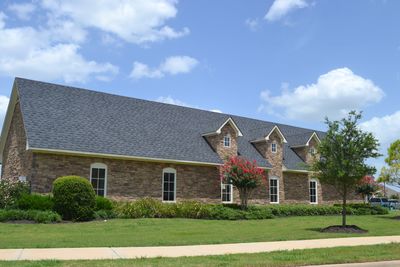 A large brick building with dormer windows and a manicured lawn.