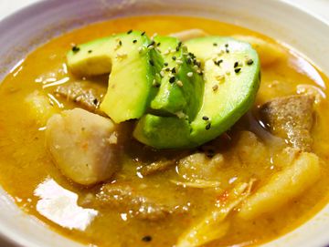 SANCHOCO, HEARTY SOUP WITH 3 ROOT VEGGIES AND CHUNKS OF MEAT. TOPPED WITH BUTTERY AVOCADO FAN