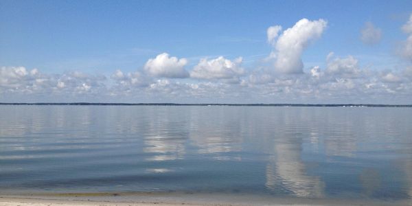 Blue sky with cotton looking clouds, still water of Rehoboth Bay.