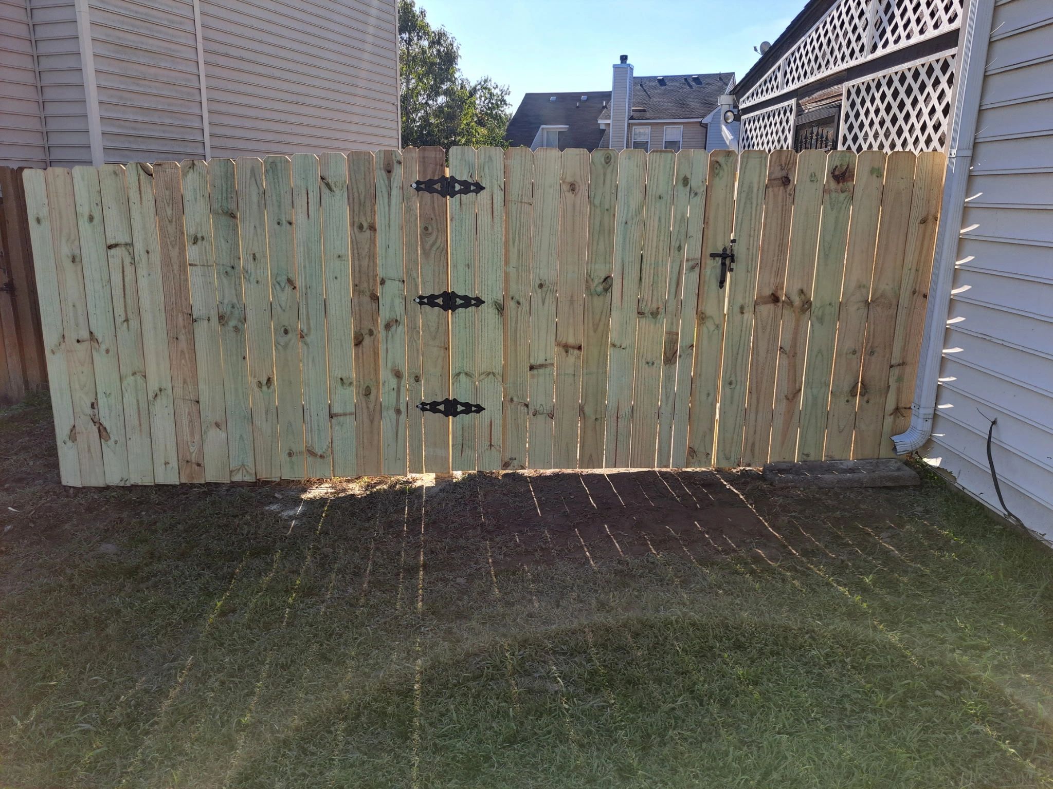 New wooden fence gate between two houses on a sunny day.