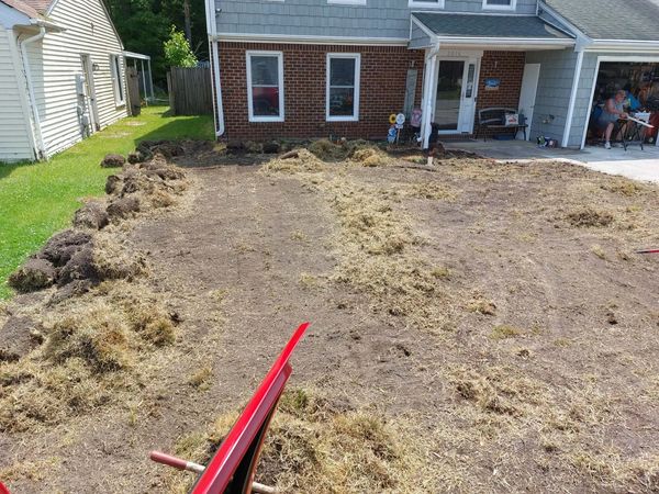 Front yard with freshly removed sod and a red wheelbarrow.
