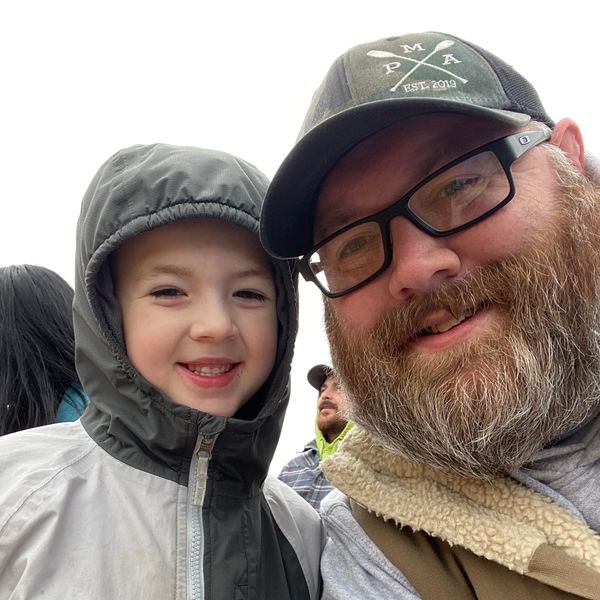 Man and child smiling in outdoor jackets.