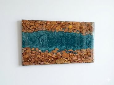 Wall art of blue resin river with stones on sides.