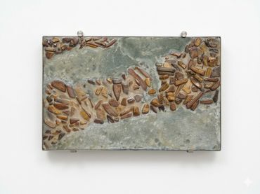 A rectangular artwork with brown stones embedded in a gray surface.