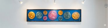 Colorful circular art pieces displayed on a blue background in a modern white gallery.