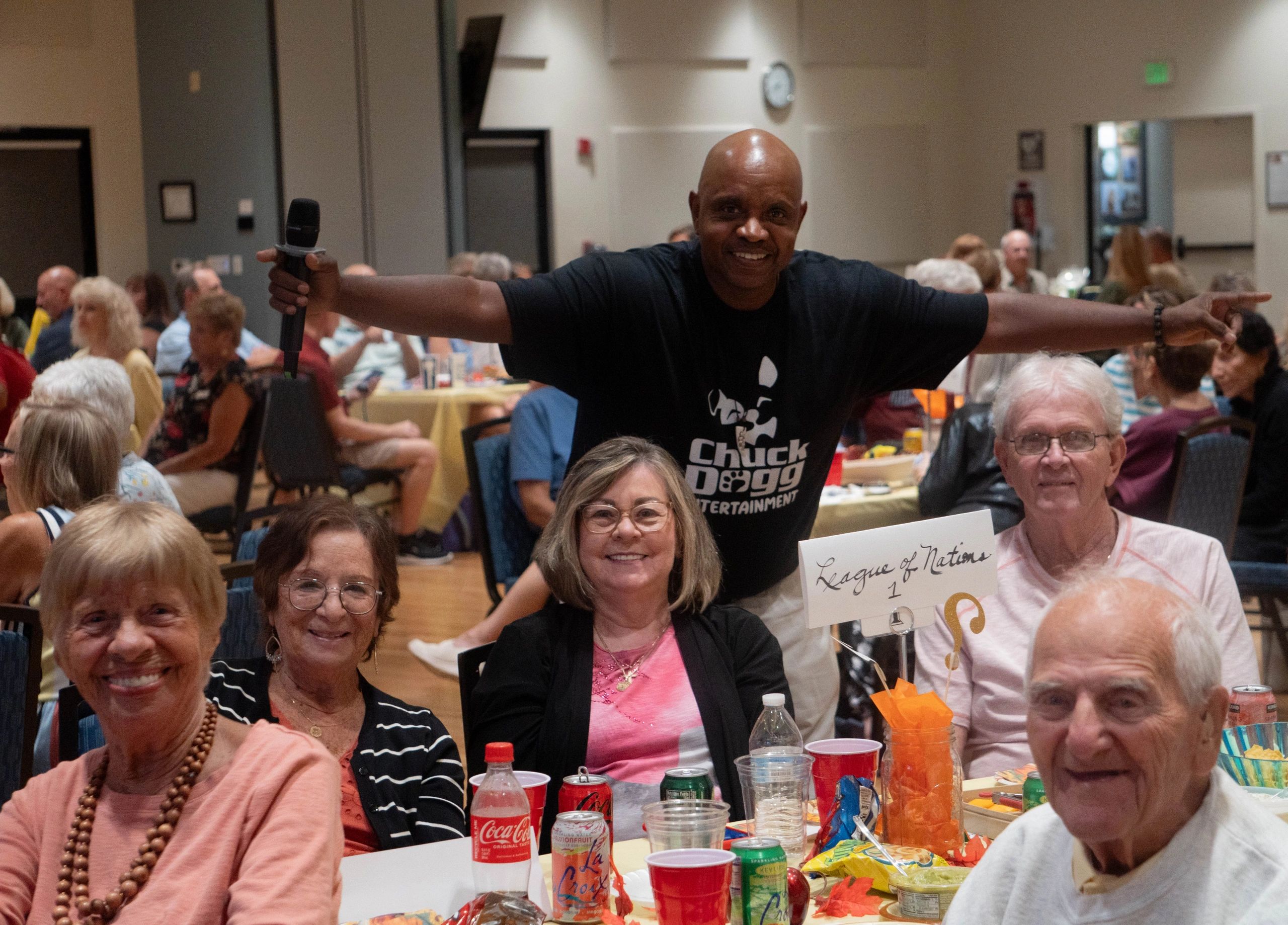 Man holding microphone behind a group at a social gathering.