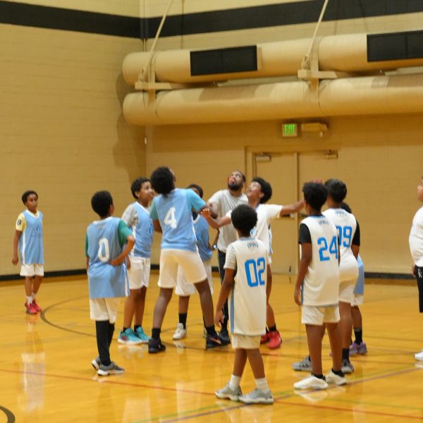 Youth basketball game in gymnasium starting with a jump ball.