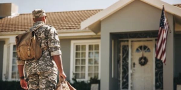 Military Person Coming Home to Front Door with American Flag 