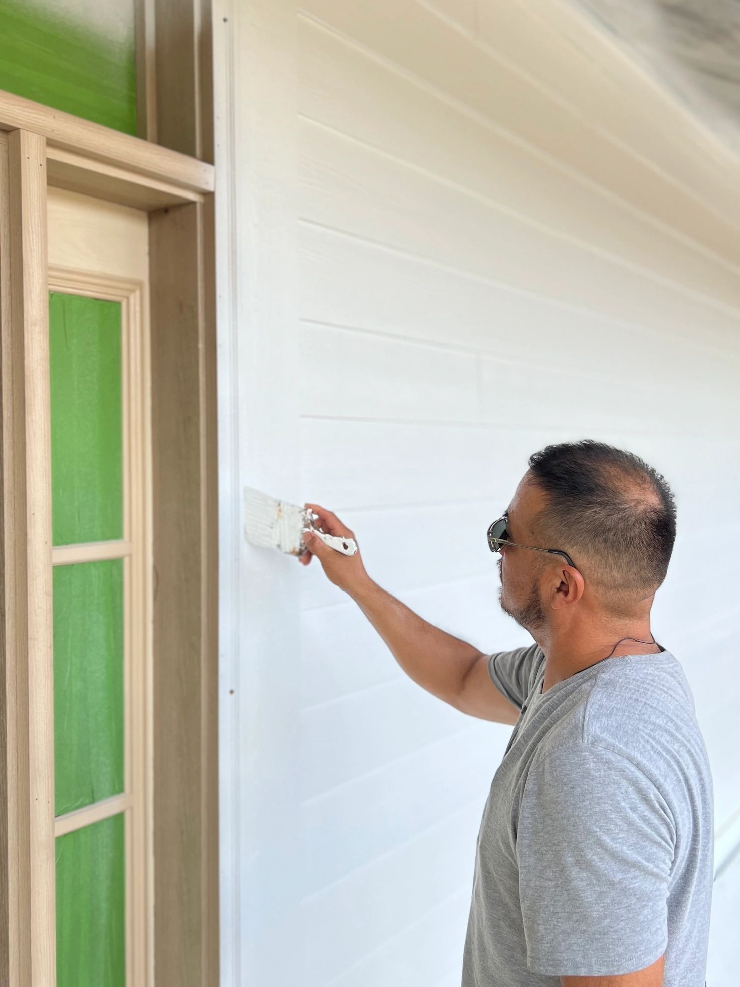 Nino Painting the front of a business building.