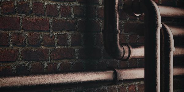 Copper plumbing pipes next to brick wall