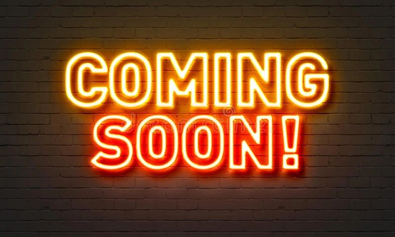 Neon sign glowing with the words 'COMING SOON!' against a dark brick wall.