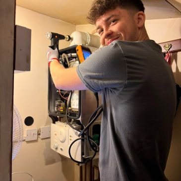 Young man repairing a device on the wall.