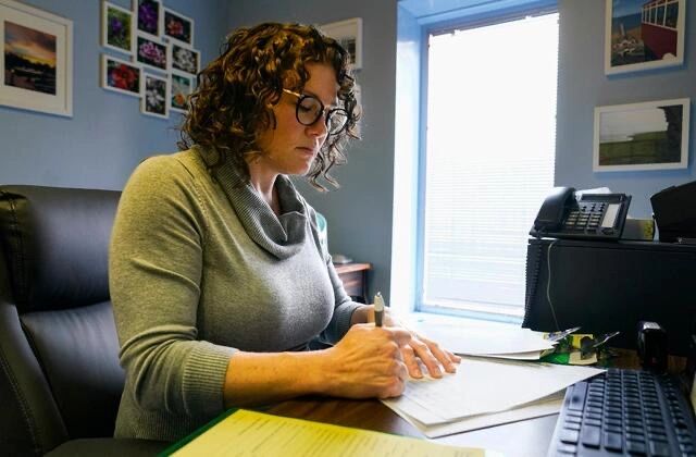 Katie McHugh, MD sits at a desk signing required forms to obtain an abortion in Indiana. 
