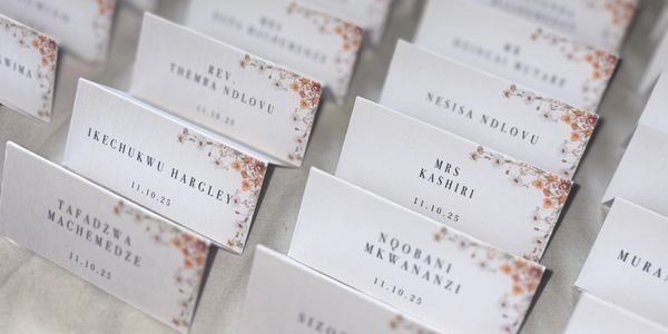 Elegant floral-themed place cards with guest names and dates for an event.