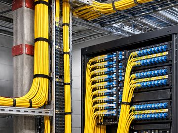 Neatly organized yellow backbone fiber cables installed in a building's network rack.