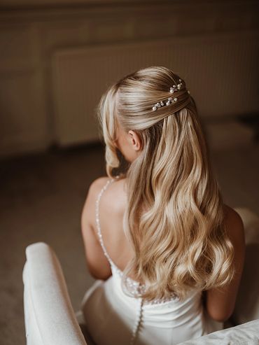 Bride with long wavy blonde hair styled elegantly with pearl hairpins.