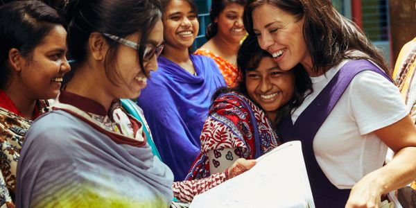 A group of women smiling and sharing a joyful moment while looking at documents.