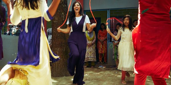 Group of women and girls joyfully skipping rope outdoors.