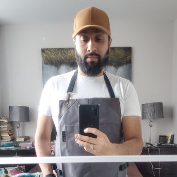 Man in an apron taking a mirror selfie.