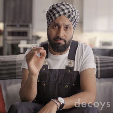 Man with a checkered headscarf making a hand gesture.