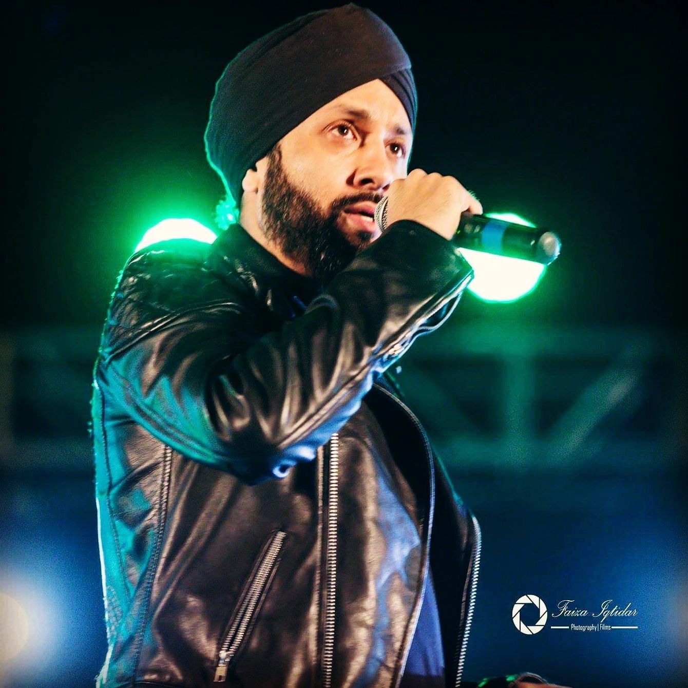 Man in a turban singing on stage with a microphone.