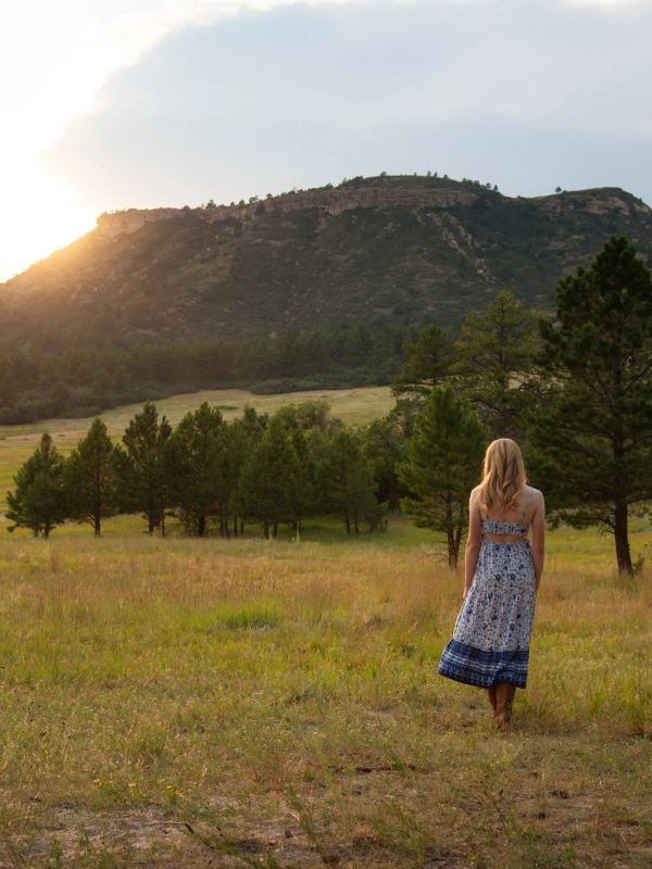 Woman in a dress looking at sunset over a mountain.